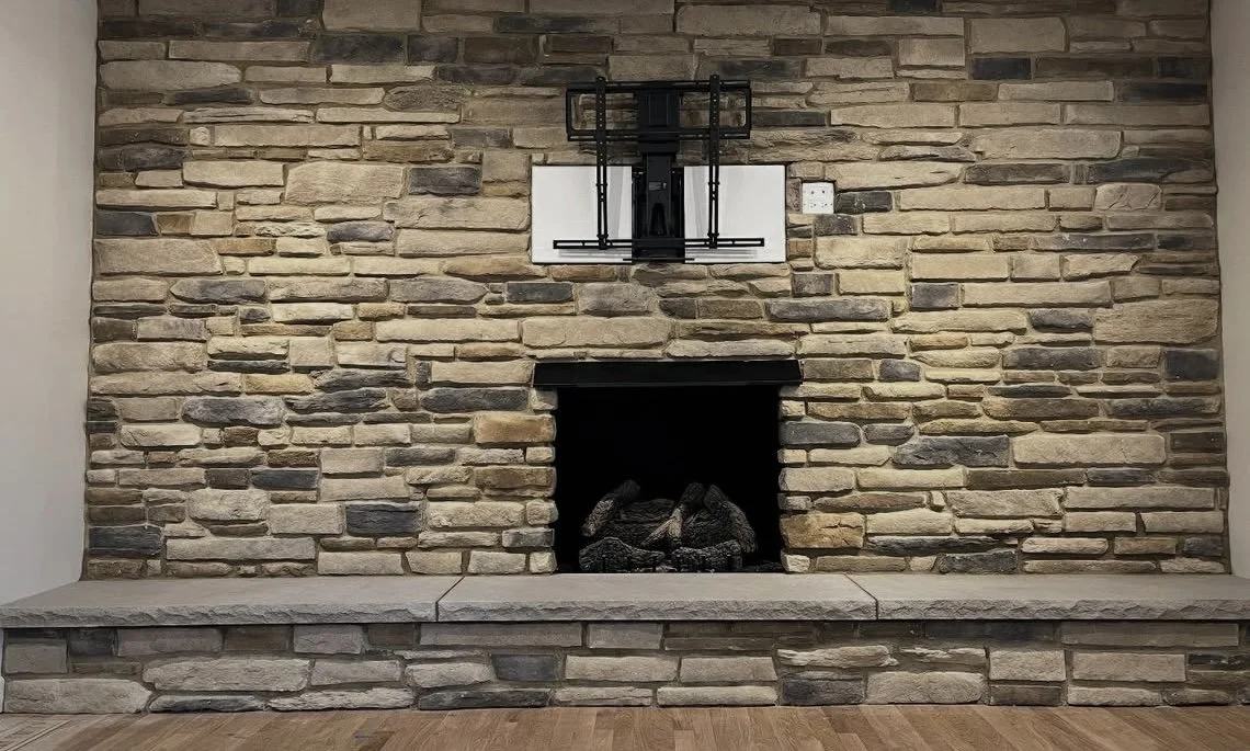 Stone fireplace with wall sconces and a wood mantel